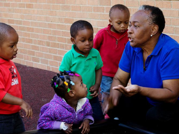 A teacher talks with a group of young learners.
