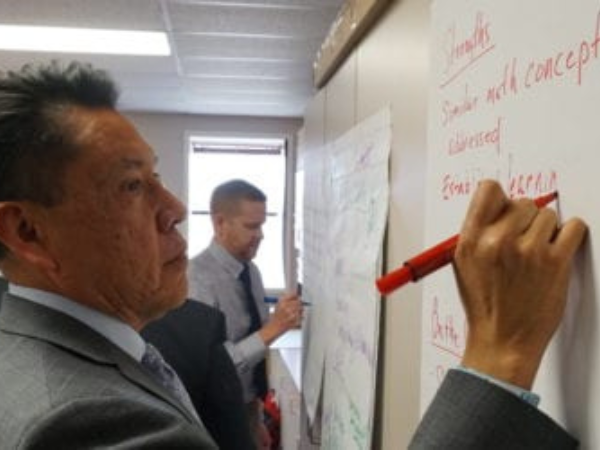 District leaders write notes on chart paper labeled, "Strengths."