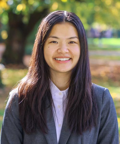Young, Chinese-American woman smiling at camera with nature background