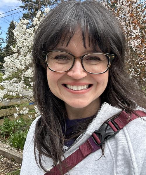 Headshot of Jenni Campbell, Assistant Director of Academic & Student Services, smiling in front of a flowering tree